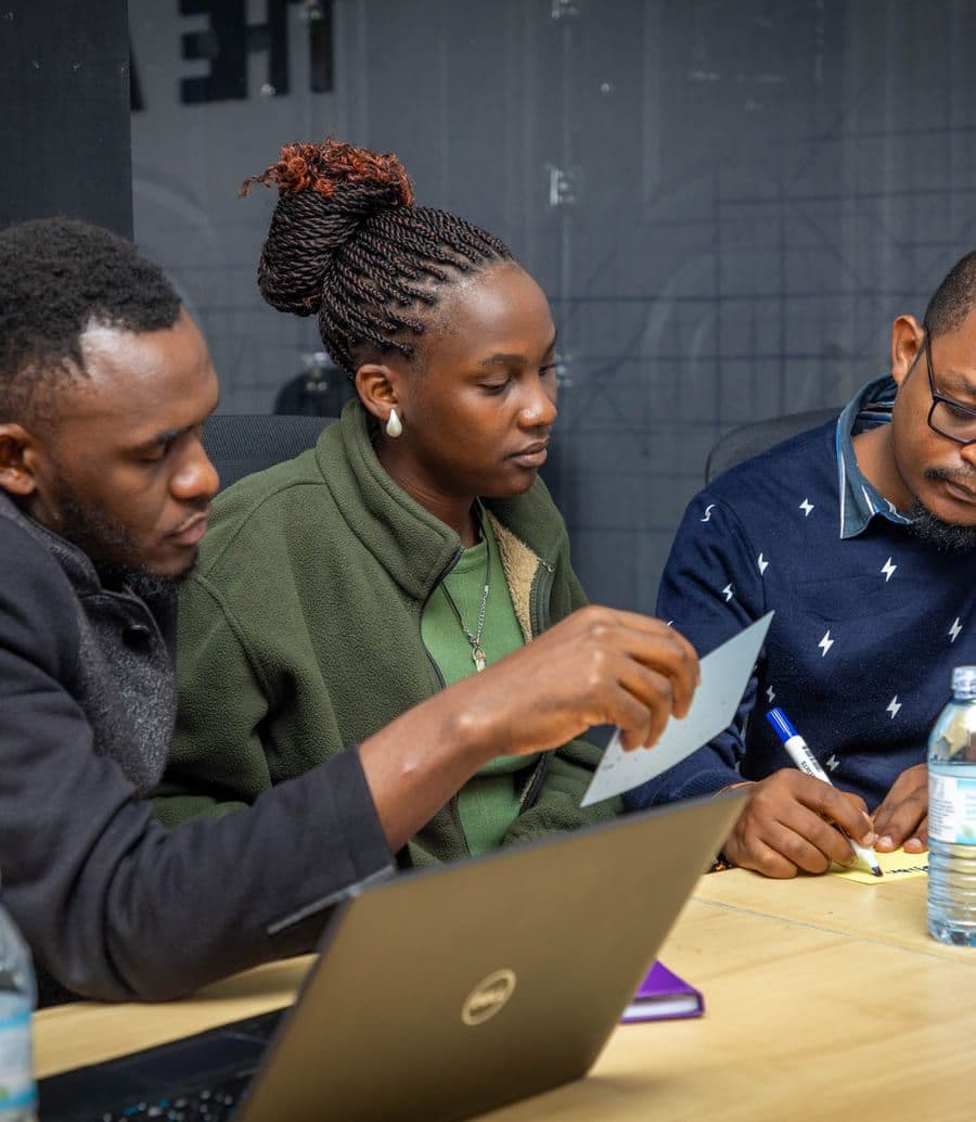Three participants leaning over a laptop together, prototyping at the AI Media Lab.