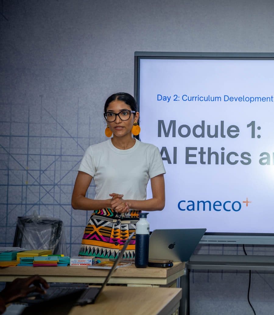 A facilitator presenting beside a screen during the ethics and AI fluency module.